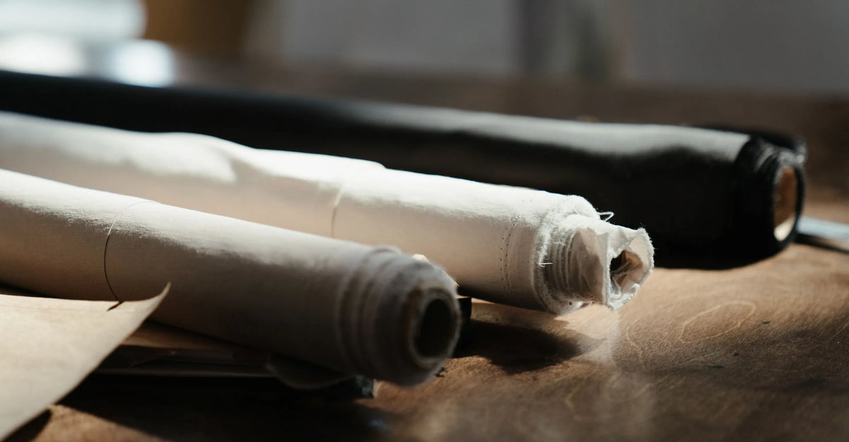 Rolls of plain cotton cloth on a wooden counter